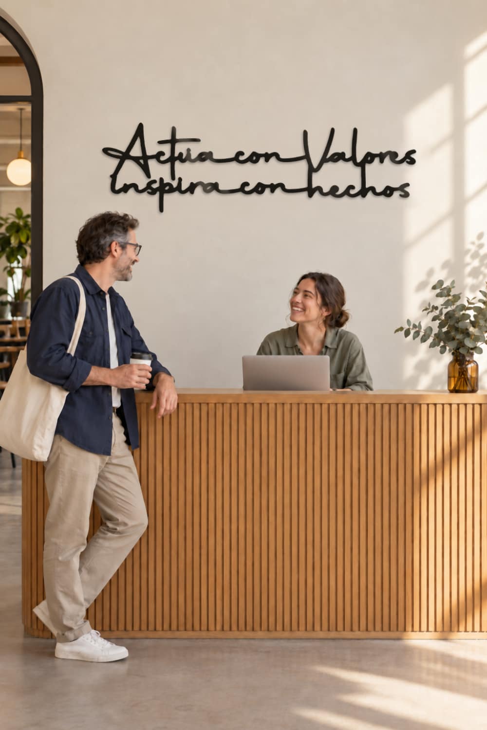 Cuadro Actúa con valores, inspira con hechos en la recepción de un coworking, con dos personas charlando