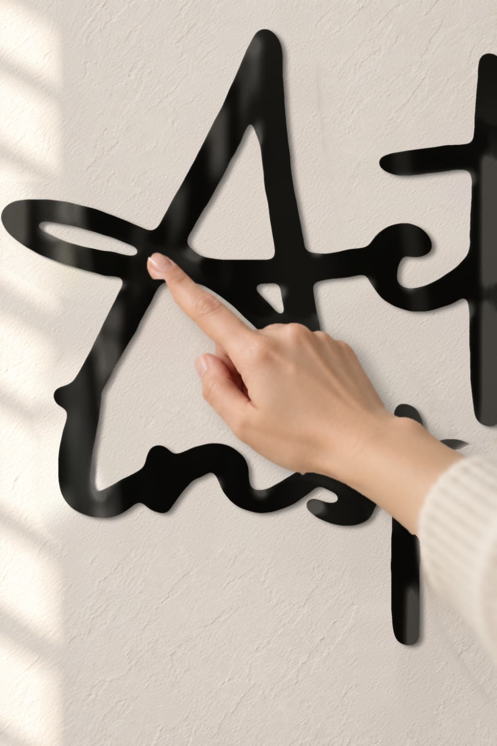 Detalle del cuadro Actúa con valores, inspira con hechos: aluminio lacado negro y una mano que lo toca