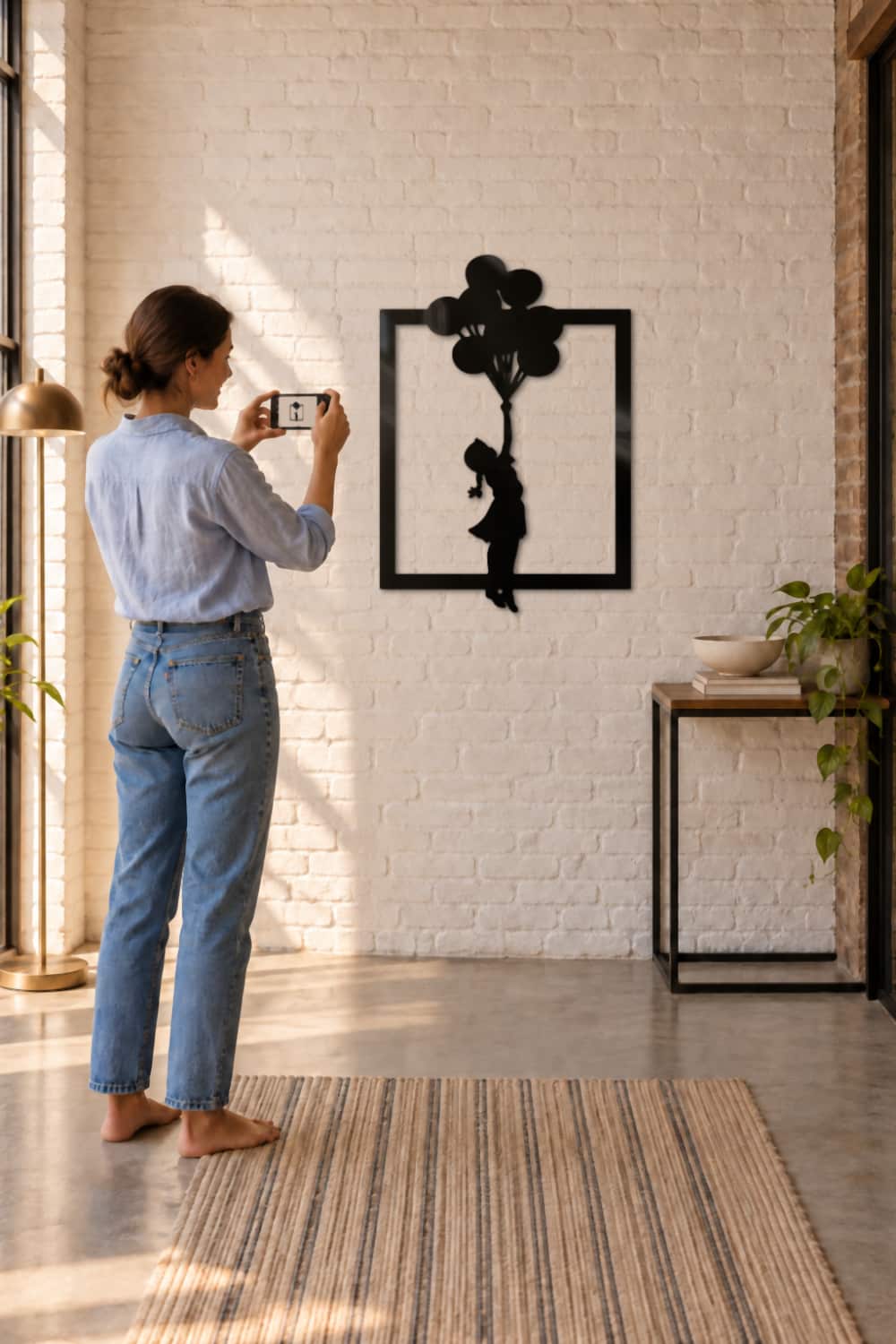 Banksy Globs: mujer fotografía con el móvil el cuadro de metal negro en un pasillo de ladrillo blanco