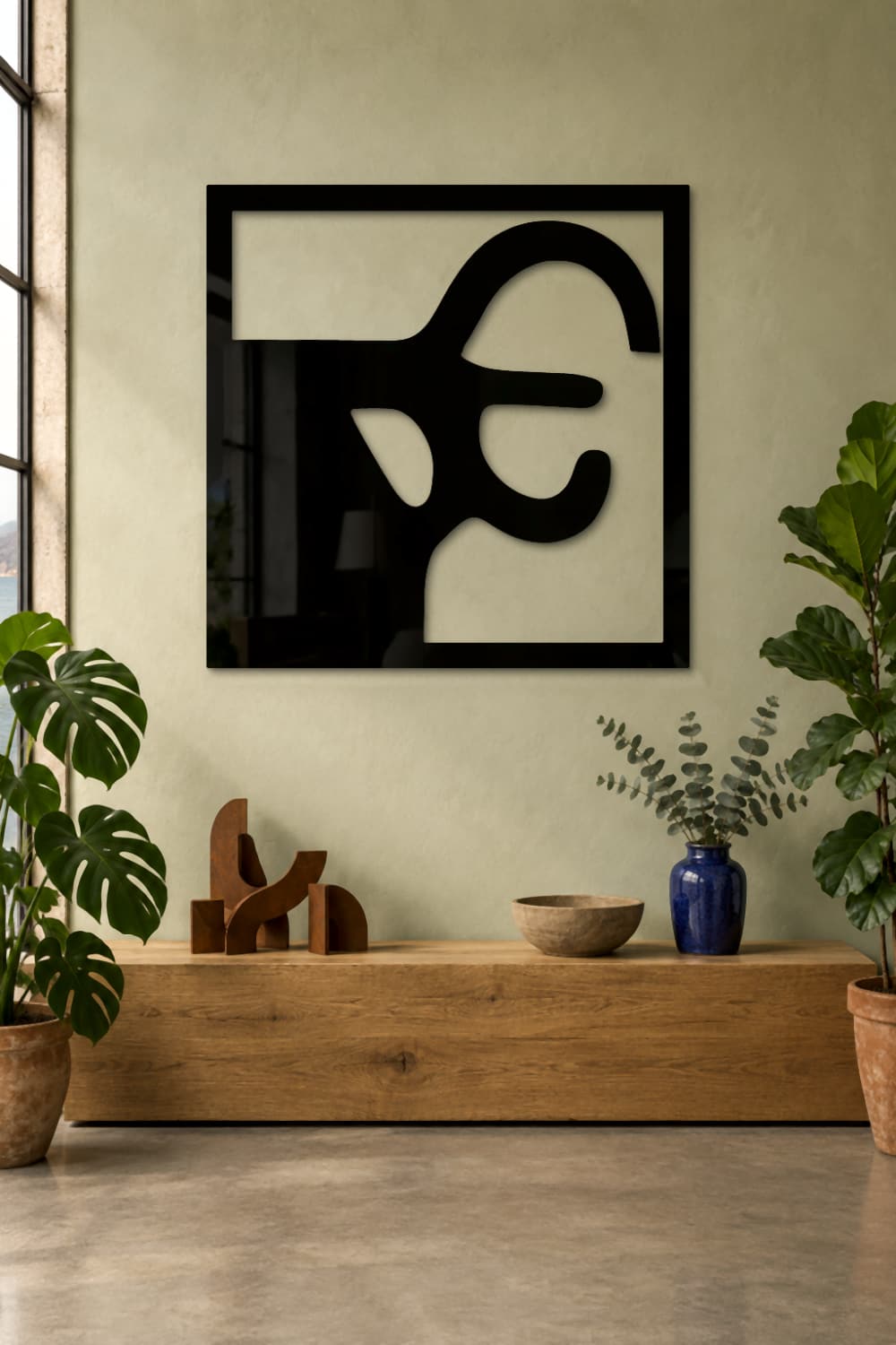 Chillida Nº 2 de aluminio negro brillante en un taller luminoso con plantas y esculturas.