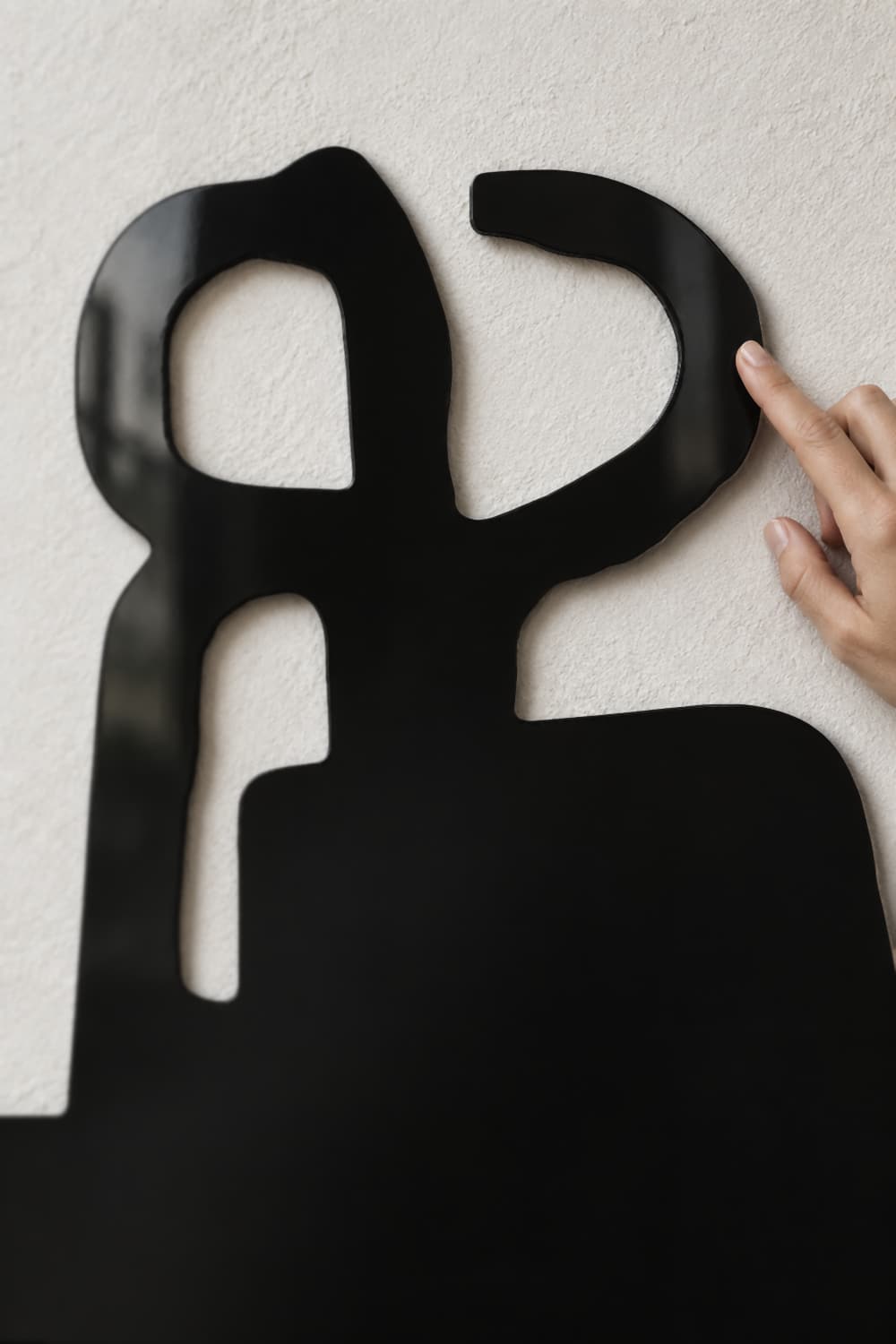 Detalle del Chillida Peine de los Vientos: aluminio negro brillante recortado y una mano tocando el borde