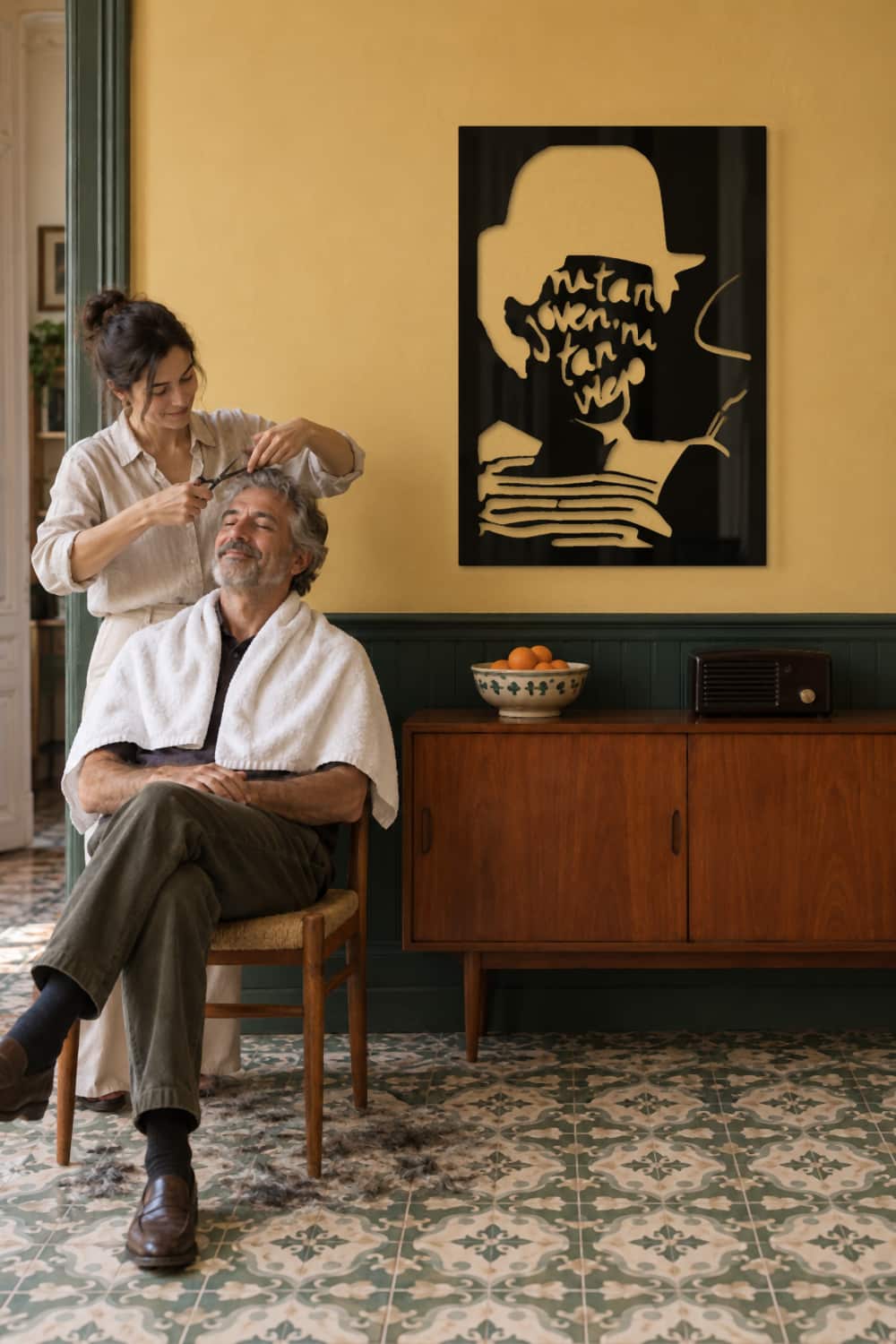 Cuadro Joaquín Sabina Ni tan viejo en pared ocre: una hija le corta el pelo a su padre en el comedor