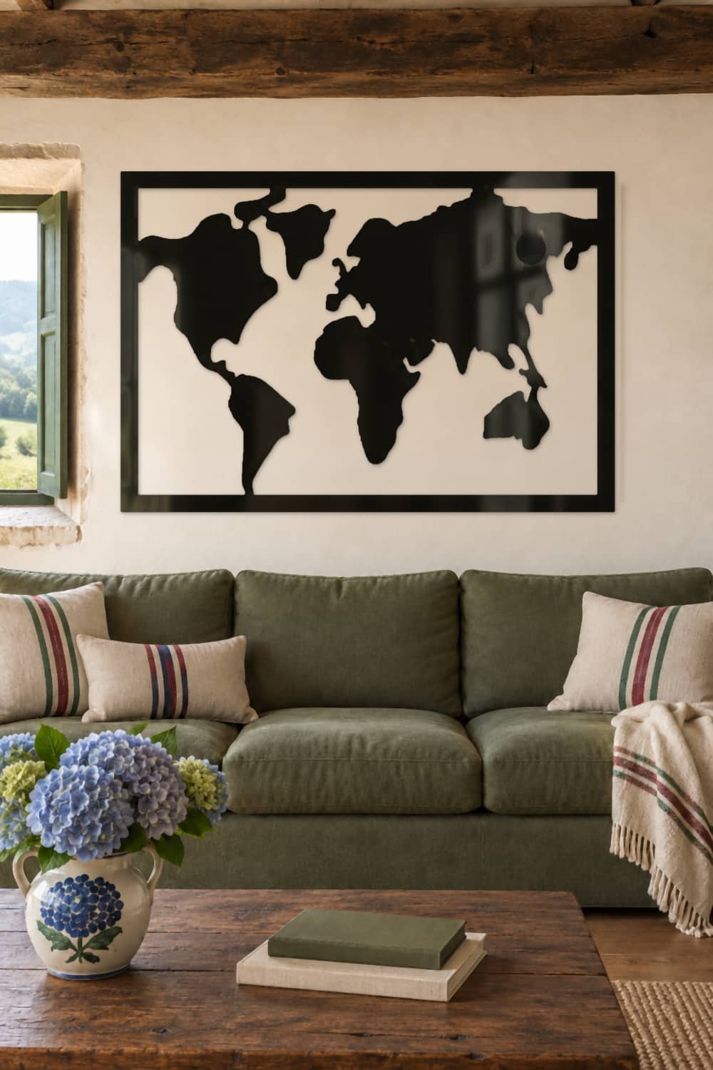 Mapa Mundi de aluminio negro brillante sobre sofá verde en un caserío con vistas al campo.