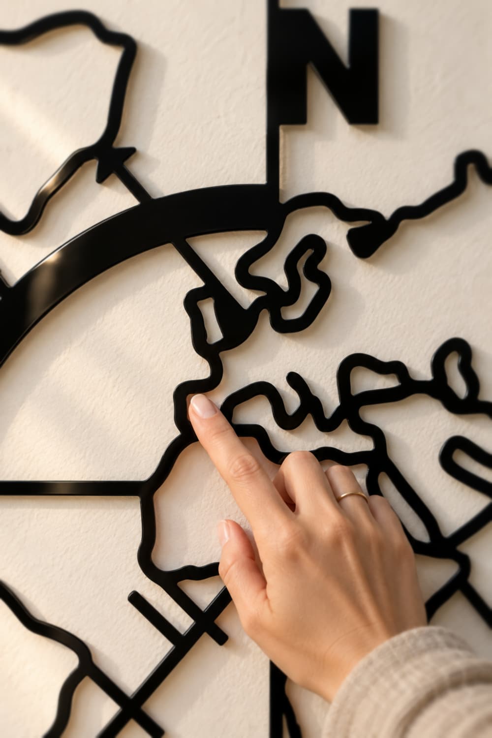 Detalle del Mapa Mundi de aluminio negro brillante: un dedo señala la península ibérica