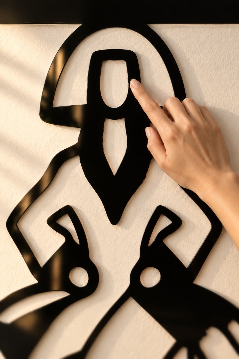 Detalle de la Menina Virgina: aluminio negro lacado brillante recortado y una mano tocando la cara