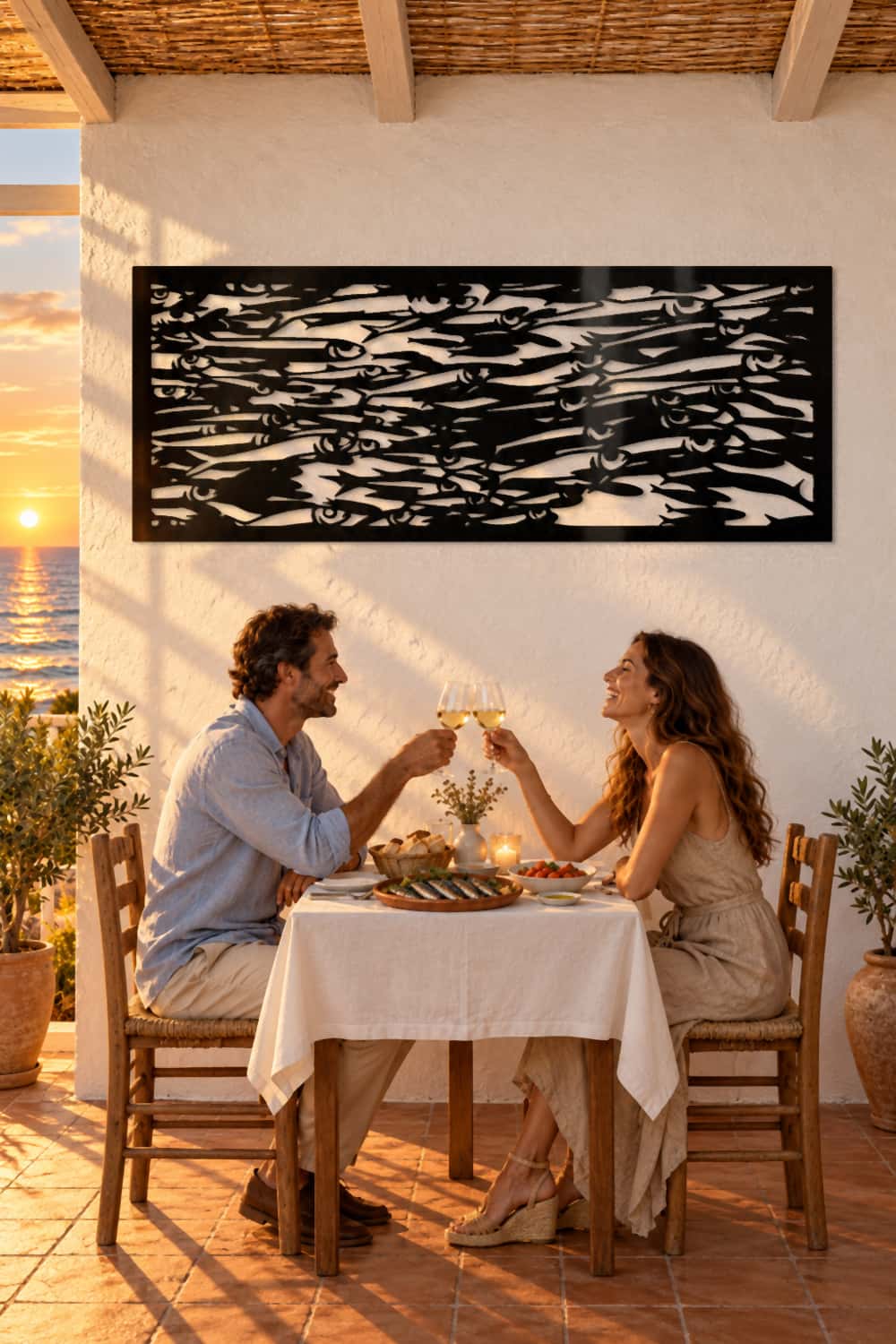 Cuadro Sardinetas en una terraza frente al mar; una pareja brinda en la cena al atardecer