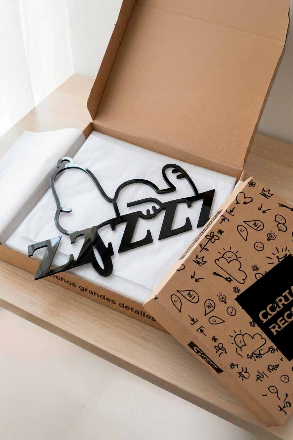 Cuadro Snoopy Durmiendo de aluminio negro en su caja de Corta y Recorta, sobre papel de seda