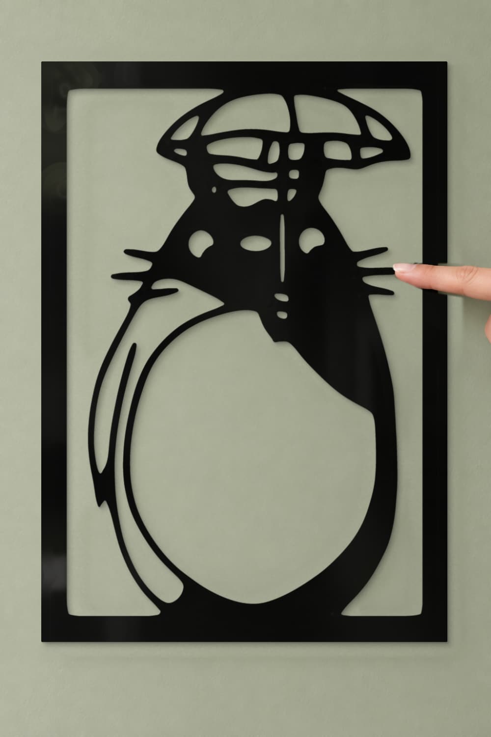 Detalle del cuadro Totoro de aluminio negro con un dedo tocando suavemente el bigote.