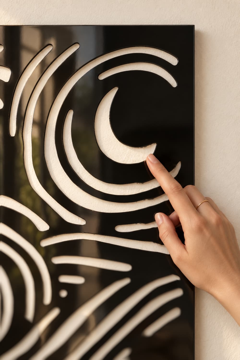 Detalle del cuadro Van G: luna creciente recortada en aluminio negro brillante al tacto de una mano