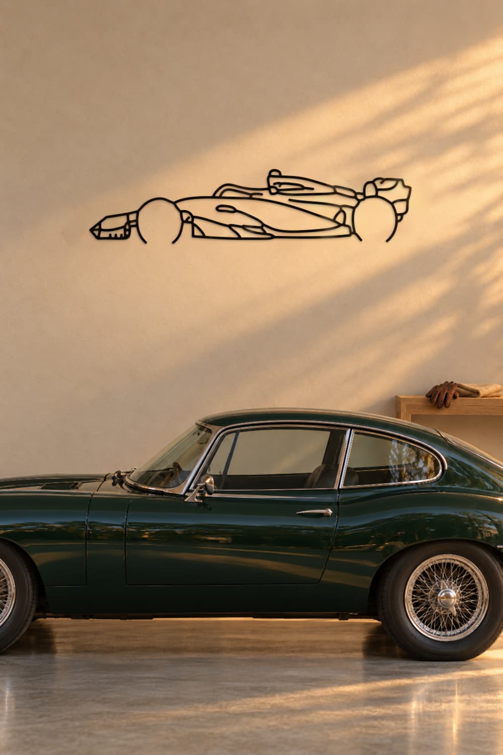 Aston Martin F1 AMR23 en garaje con coche clásico verde y luz de atardecer