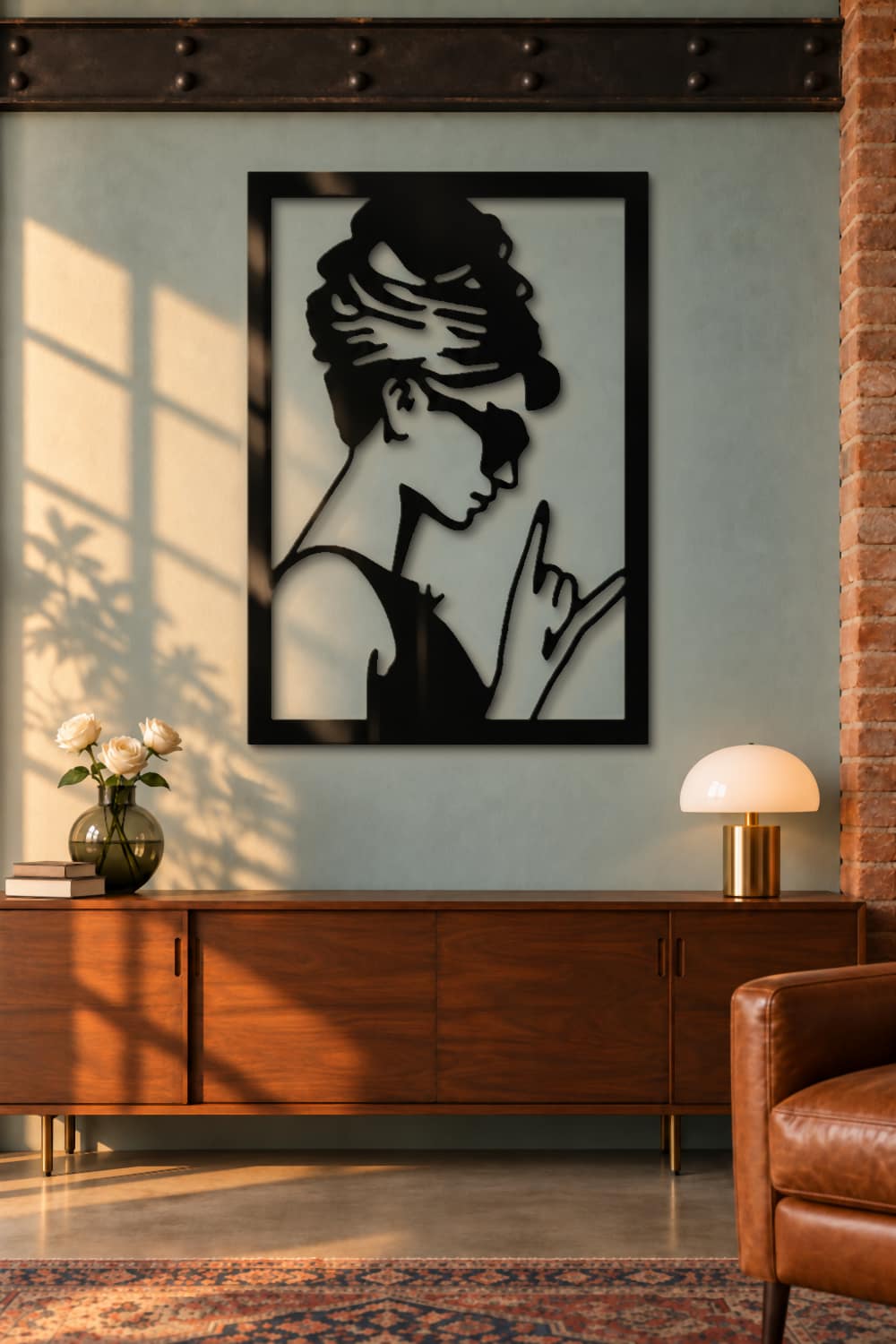 Cuadro de metal Audrey Hepburn en negro brillante sobre aparador de nogal en un loft con pared verde salvia