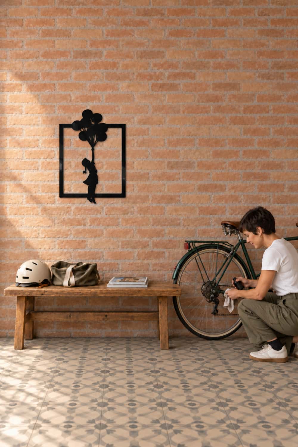 Cuadro Banksy Globs 70×50 en pared de ladrillo, junto a una mujer que engrasa su bicicleta