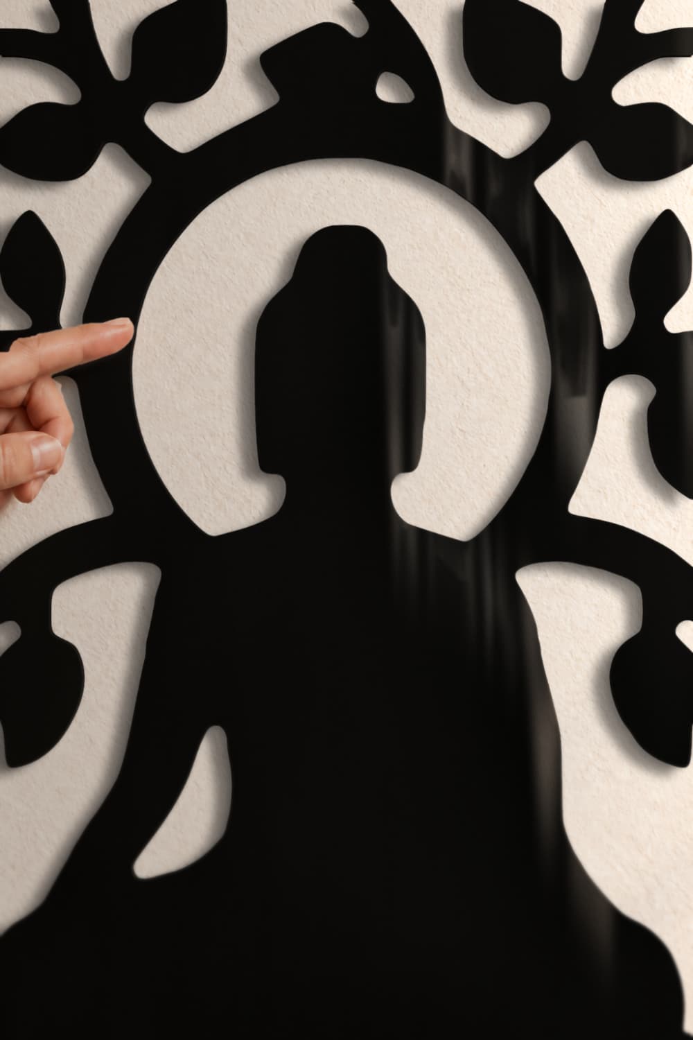 Detalle del Budha De La Vida: halo y Buda en aluminio negro lacado brillante con su sombra en la pared