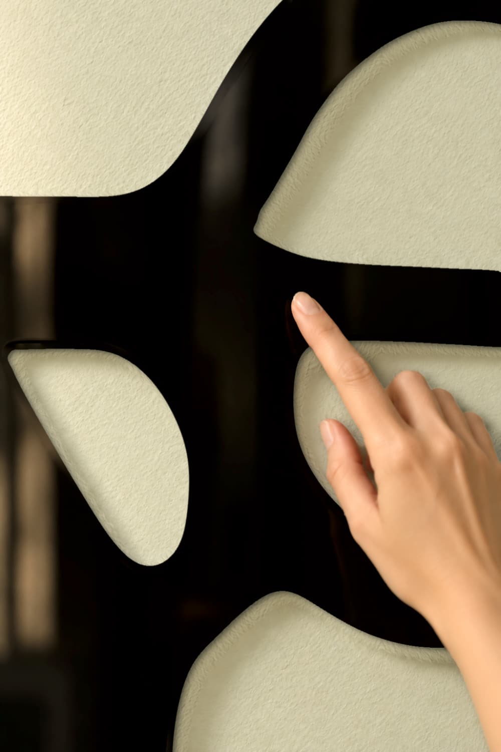 Chillida Nº 2: detalle del aluminio negro brillante y una yema tocando suavemente la pieza.