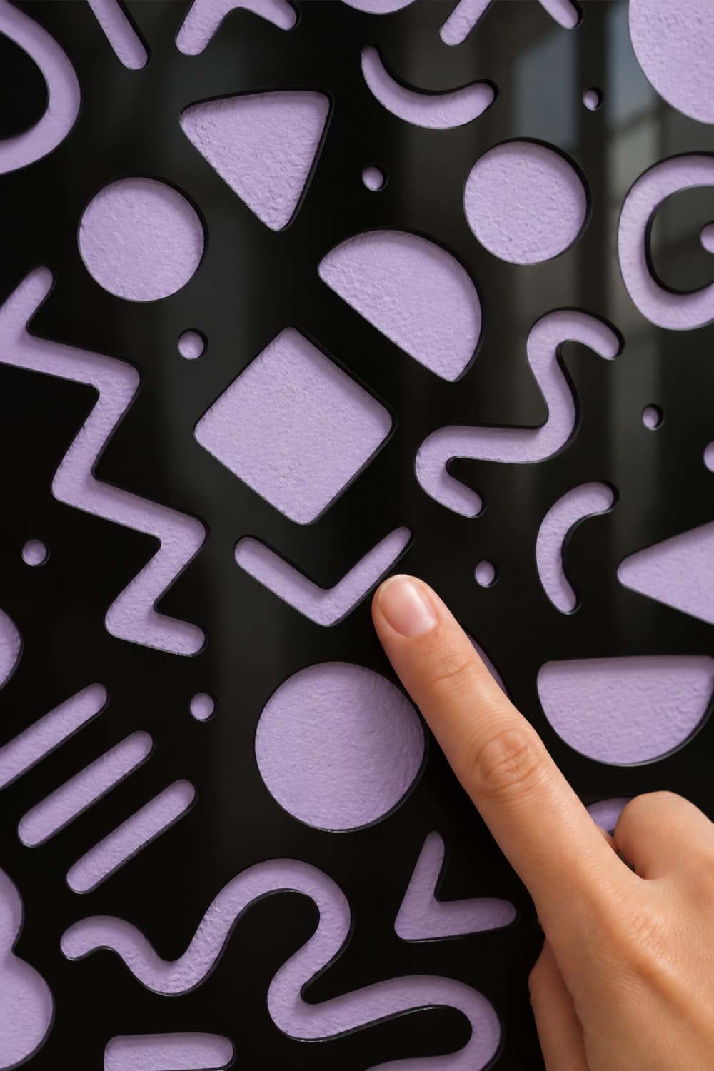 Estrambotic, detalle del aluminio negro brillante calado con una yema tocando la superficie