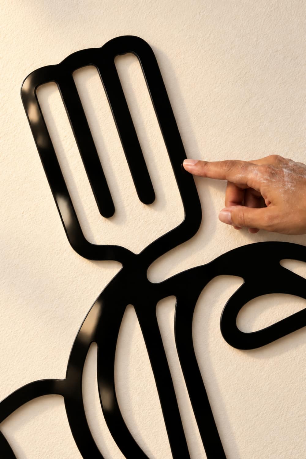 Detalle del cuadro Kitchen: espátula y plato en aluminio negro brillante separado de la pared