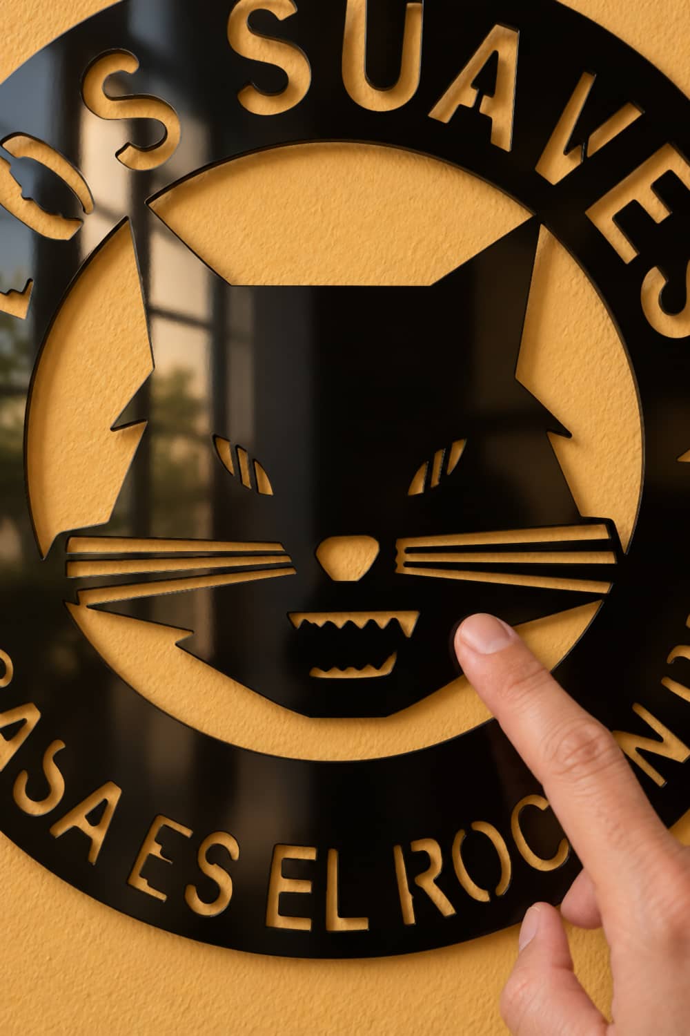 Los Suaves: detalle del gato en aluminio negro brillante con un dedo sobre el metal.