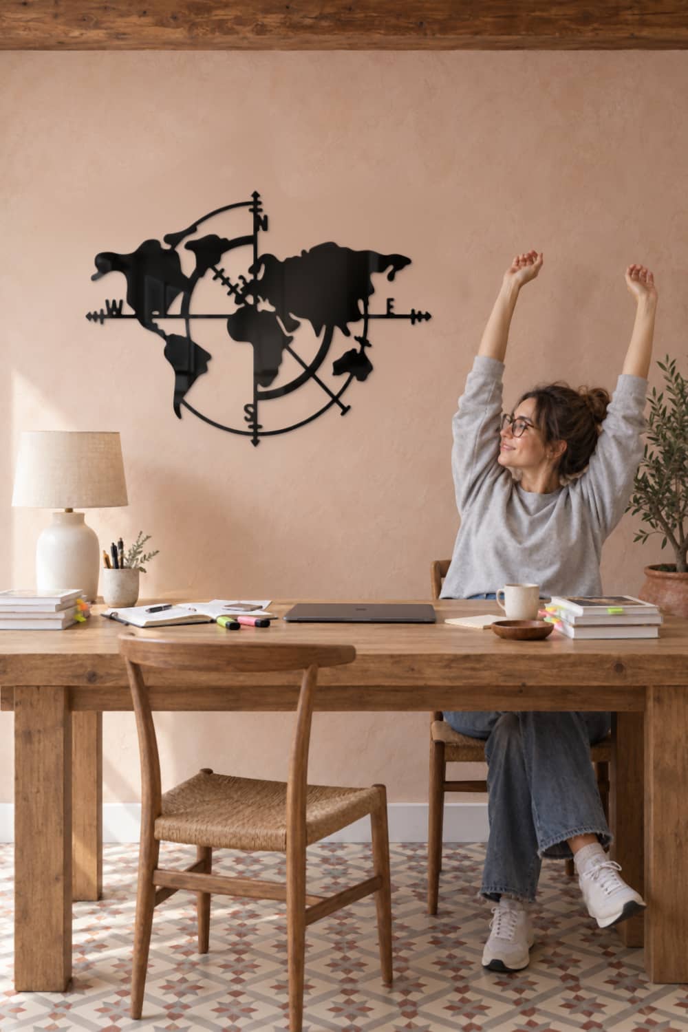 Cuadro Mapa de los Vientos de metal en estudio con pared rosa: mujer se estira en su mesa de trabajo