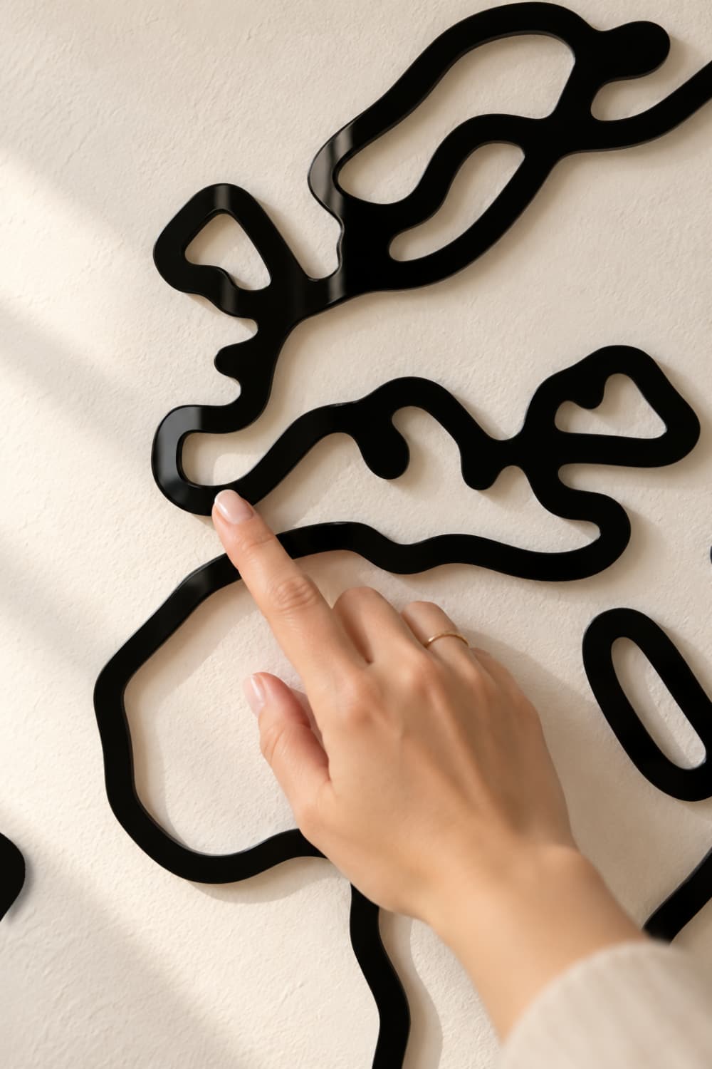 Detalle del Mapa Slim: una mano toca la línea de Europa en aluminio negro lacado brillante