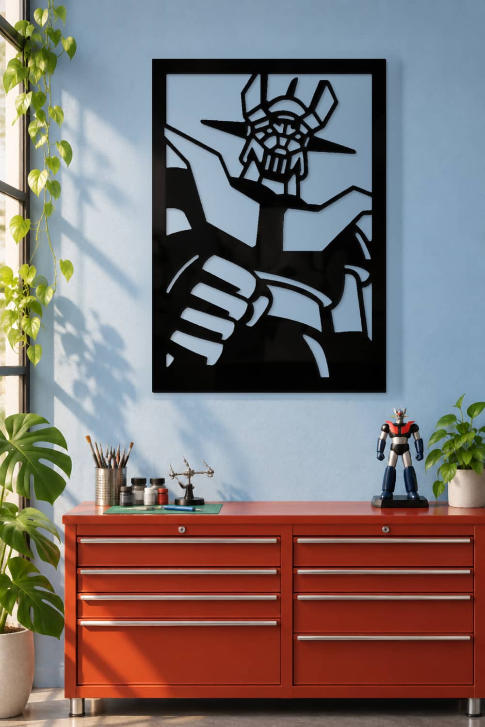 Mazinger Z de metal negro brillante en un estudio creativo con plantas y cajonera roja.
