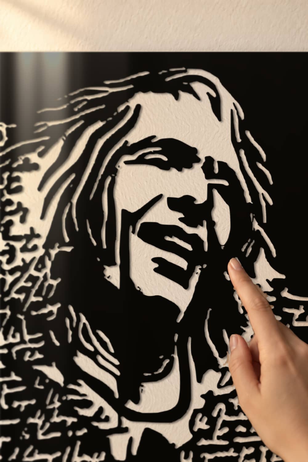Detalle del retrato calado de Robe Iniesta en aluminio negro brillante, con la pared asomando