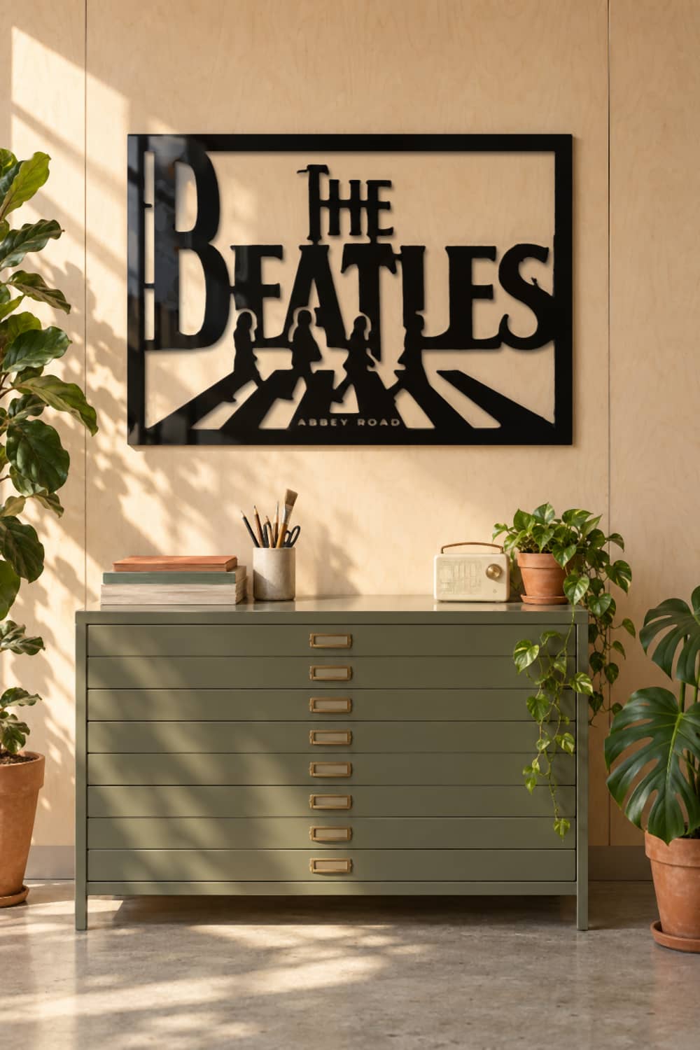 Cuadro The Beatles Abbey Road en aluminio negro brillante sobre una cajonera de planos verde en un estudio
