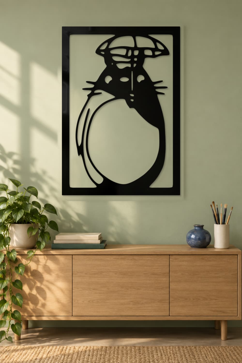 Totoro de metal negro brillante en un coworking creativo con pared verde salvia.