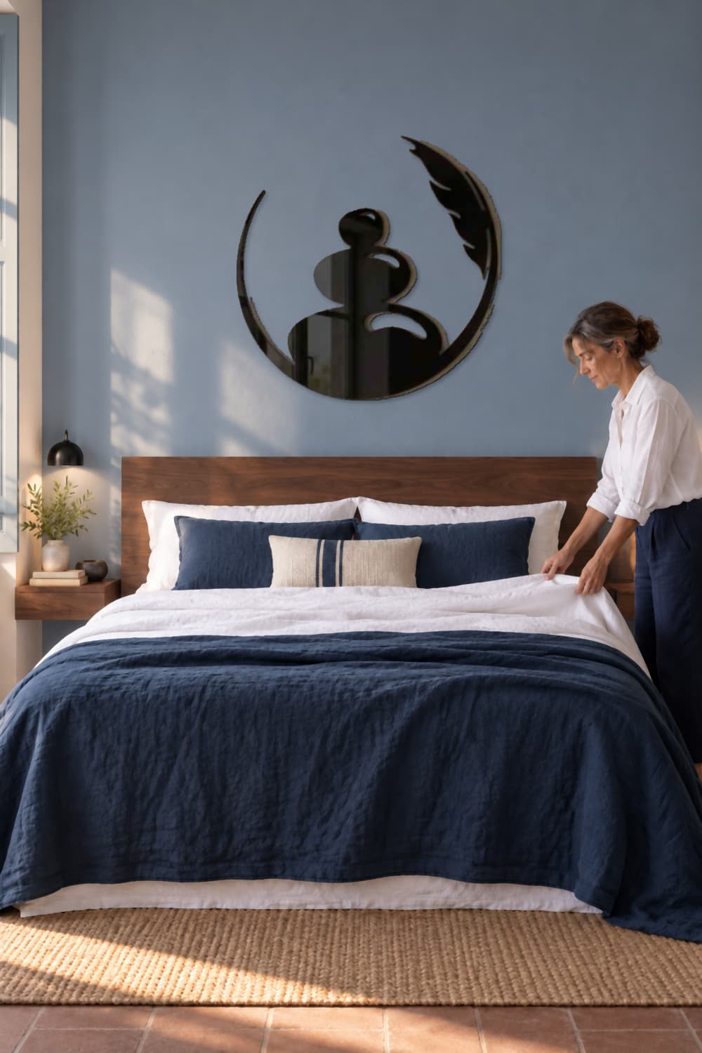 Zen Art en un dormitorio azul mientras una mujer prepara la cama con luz natural.